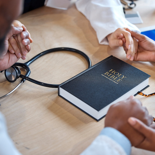 Hands, bible and a healthcare team praying for a miracle curing a meeting in a hospital office toge.