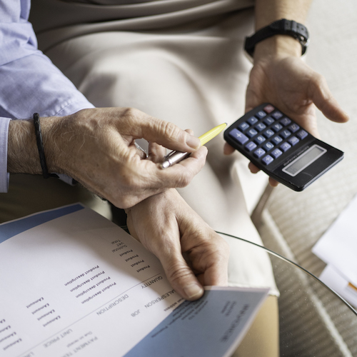 People's hands holding a calculator, pen, and documents, discussing financial planning